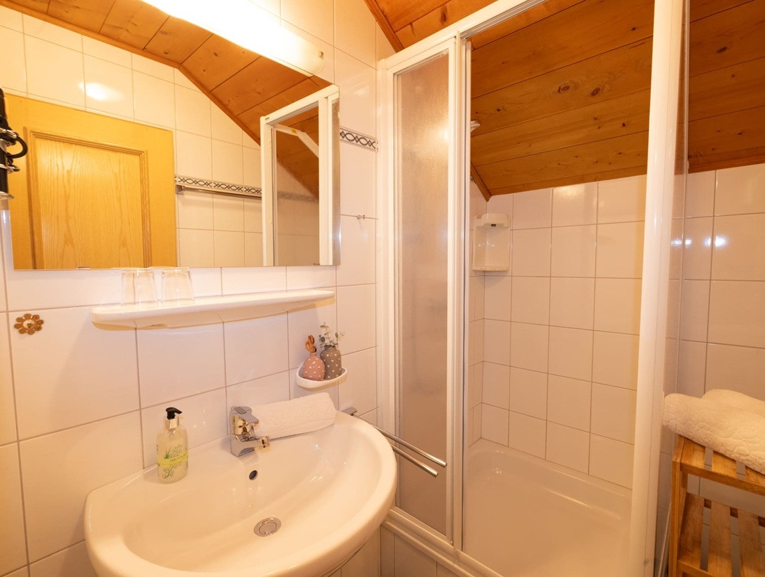 Kompaktes Badezimmer mit Dusche, Waschbecken und Holzdekor an der Decke