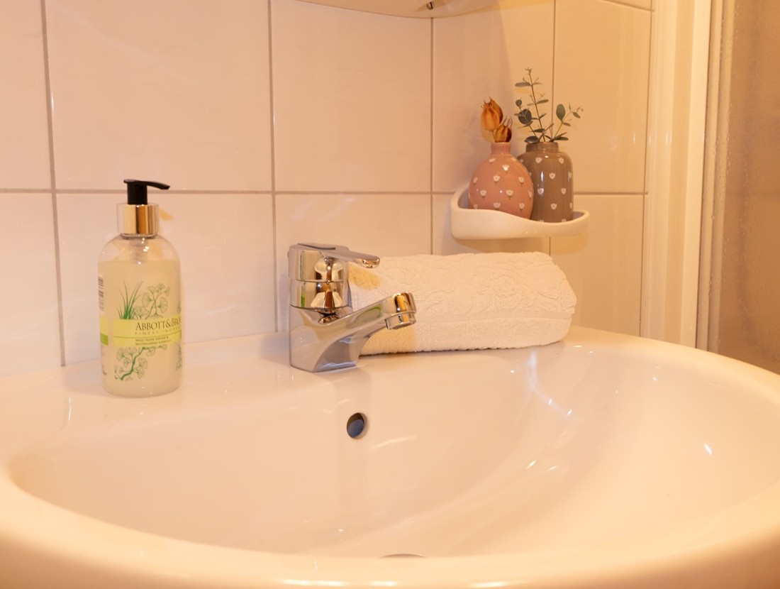 Ein Waschbecken mit Seifenspender, Handtuch und dekorativen Vasen auf Fliesenhintergrund