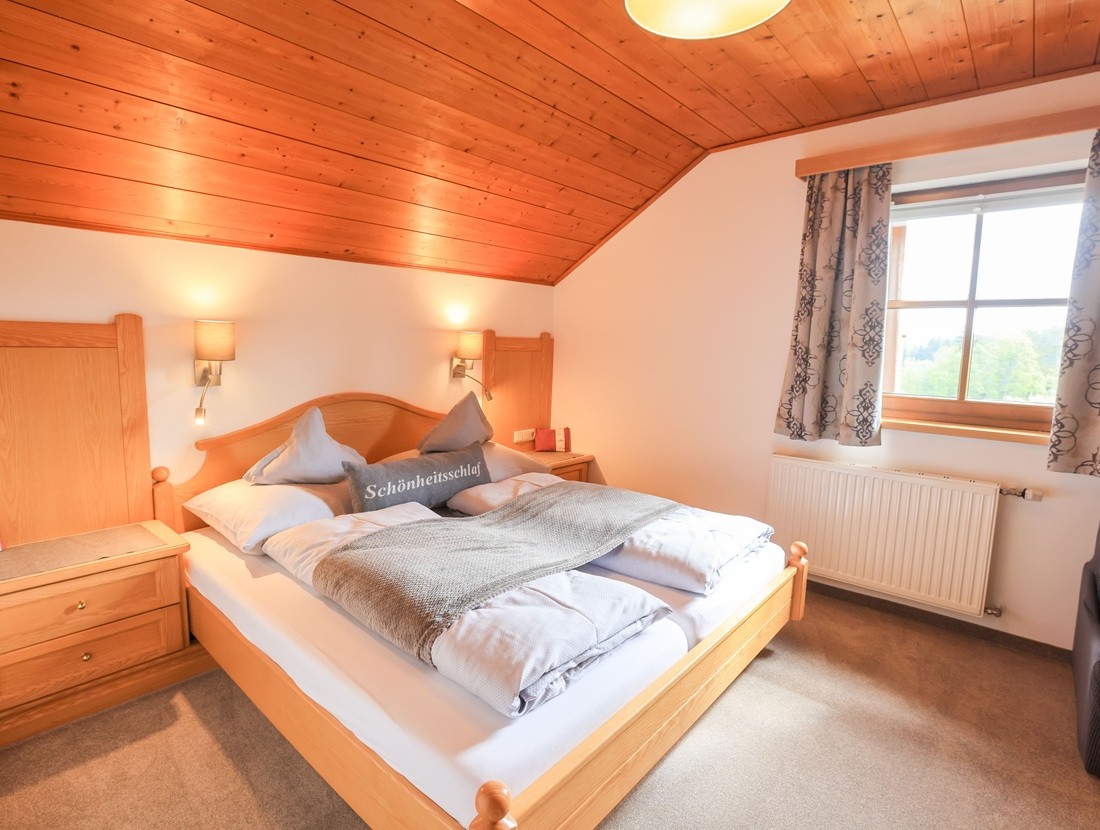 Gemütliches Schlafzimmer mit Holzmöbeln und einem großen Fenster