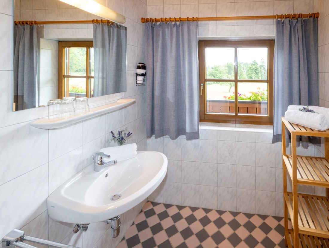 Helles Badezimmer mit großem Fenster, blauem Vorhang und Waschbecken